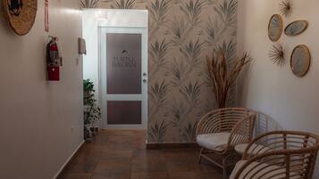 A hallway with a door labeled "Turtle Bay Inn," wicker chairs, a fire extinguisher, and wall-mounted mirrors.