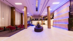 A spacious lobby with a central seating area, a staircase, and a reception desk. - Hotel Transilvania (Alba Iulia)