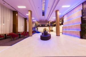 Un vestíbulo amplio con zona de estar central, una escalera y un mostrador de recepción.