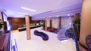 A modern lobby with a curved seating area, a reception desk, and a staircase leading to an upper level. - Hotel Transilvania (Alba Iulia)