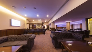 A hotel lobby with a bar area, seating arrangements, and a carpeted floor. - Hotel Transilvania (Alba Iulia)