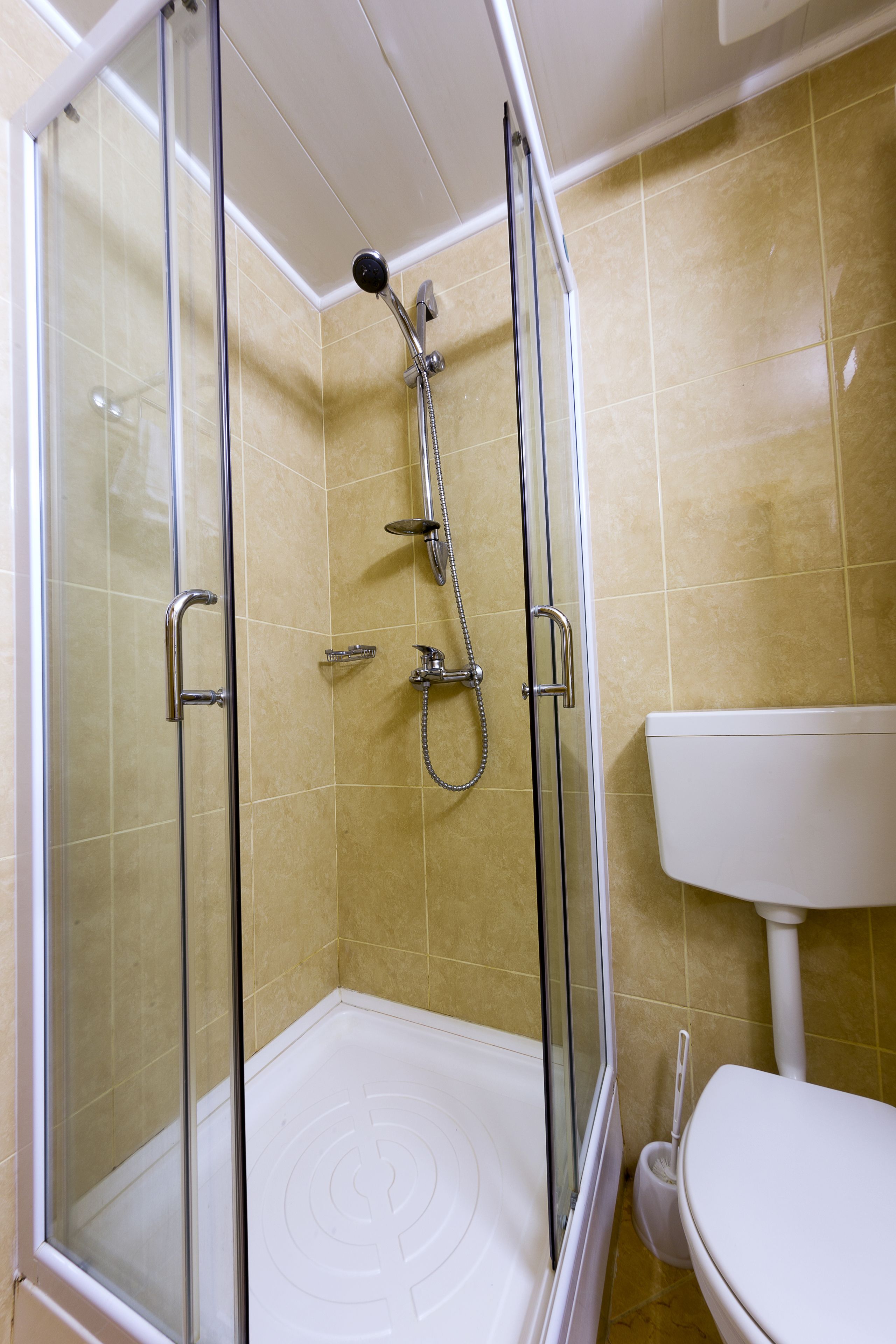A glass-enclosed shower with a handheld showerhead, a handheld showerhead, and a handheld showerhead.