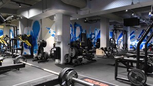 A gym with weightlifting equipment, mirrors, and blue wall murals. - Hotel Moldova (Iasi)