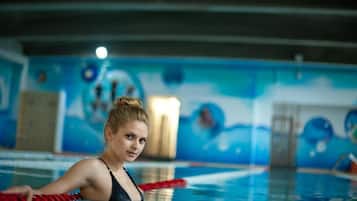 Een binnenzwembad, ligstoelen bij het zwembad