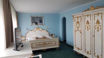 A bedroom with a bed, a dresser, a desk, and a wardrobe.