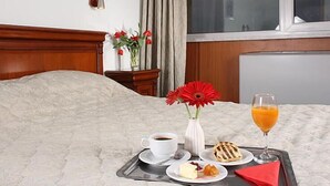 A neatly made bed with a tray of breakfast items including coffee, a glass of orange juice, a pastry, and a small plate of food. - Hotel Moldova (Iasi)