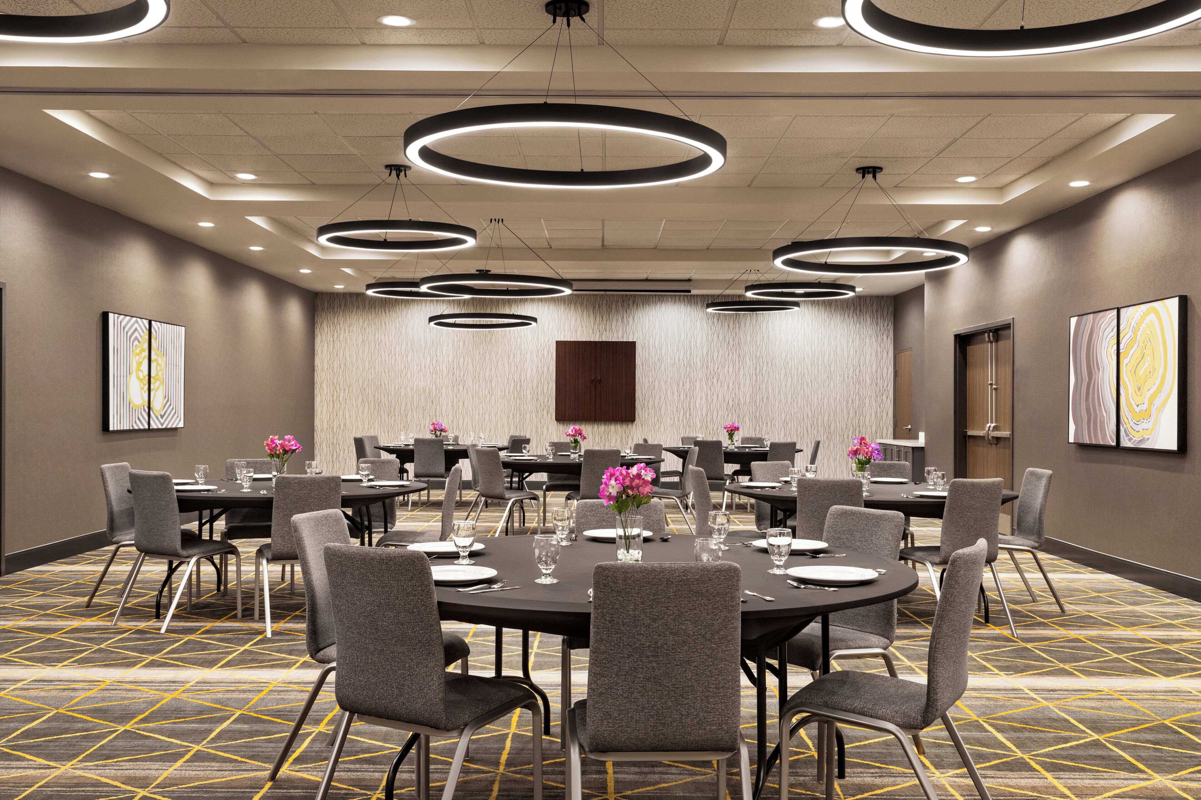 A conference room with round tables, chairs, and modern lighting fixtures.