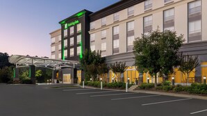 Ein Holiday Inn Hotel mit zeitgemäßer Fassade, einem überdachten Eingang und einem Parkplatz.