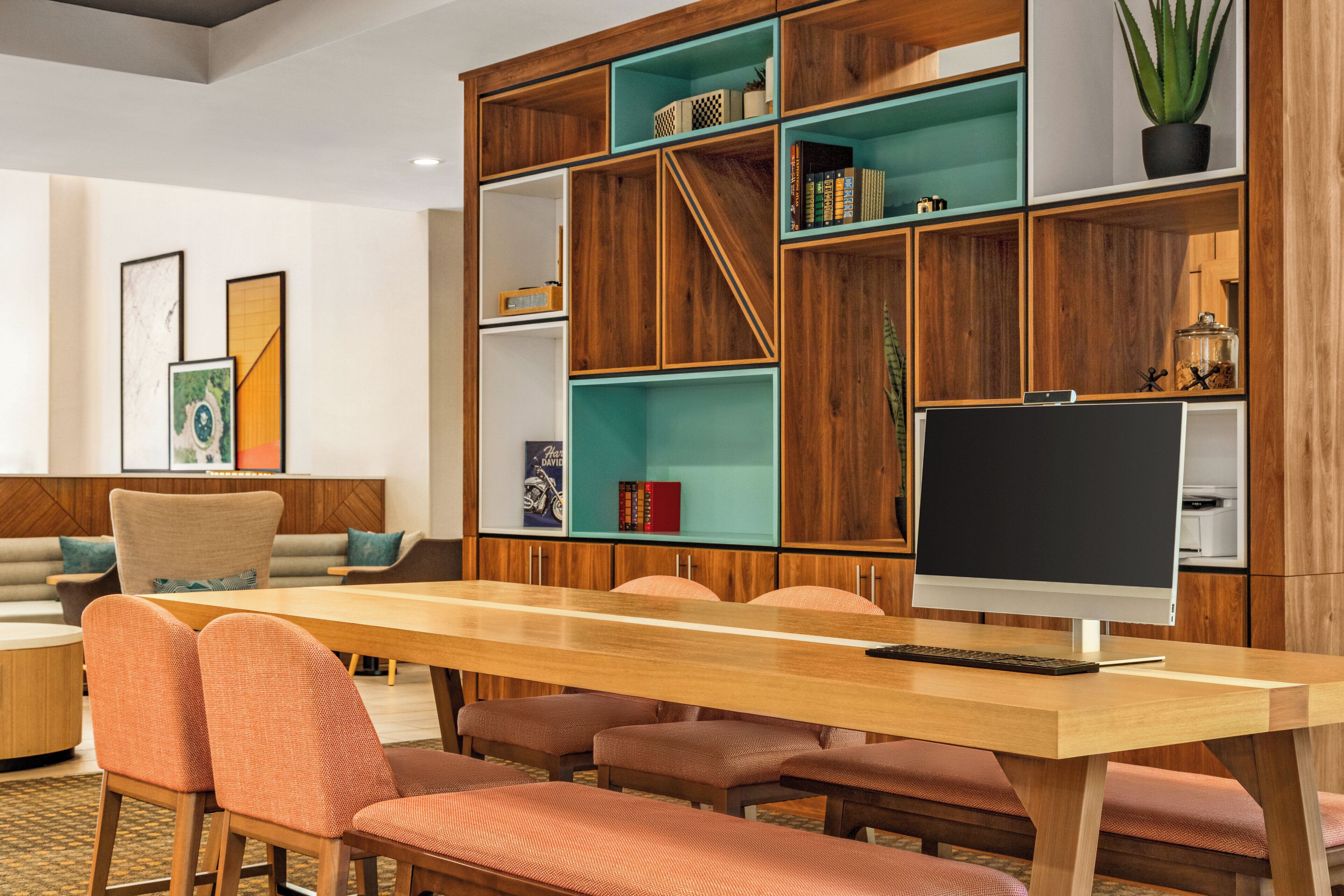 A modern library with wooden bookshelves, a large table, and comfortable seating.