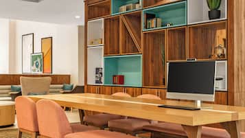 A modern library with wooden bookshelves, a large table, and comfortable seating.
