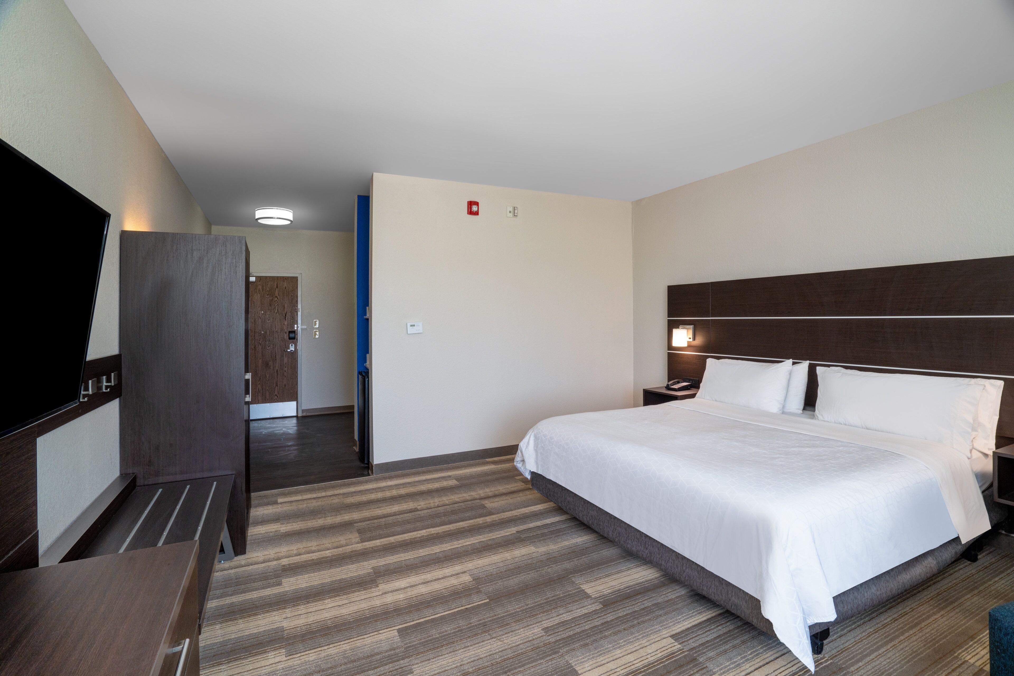 A hotel room with a bed, bedside table, and a wardrobe.