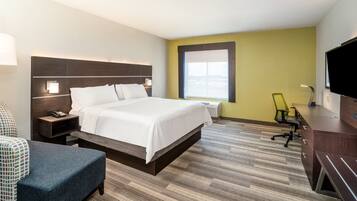 A hotel room with a large bed, bedside tables, a desk, a chair, a television, and a window with a view.