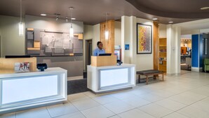 A reception area with a modern design, featuring a reception desk, a bench, and a wall with a colorful pattern. - Holiday Inn Express and Suites Winona North by IHG (Winona)