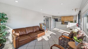 A modern hotel lobby with a brown leather sofa, a small table with chairs, a reception desk, and a kitchen area in the background. - Rodeway Inn Stockton Highway 99 (Stockton)