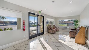 A spacious lobby with a fire extinguisher, an exit sign, a reception desk, and a view of the outdoors. - Rodeway Inn Stockton Highway 99 (Stockton)