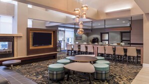 A modern hotel lobby with a bar area, seating arrangements, and a fireplace. - Residence Inn Florence Marriott (Florence)