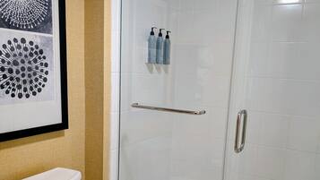 A bathroom with a toilet, a glass shower enclosure, and a framed artwork on the wall.