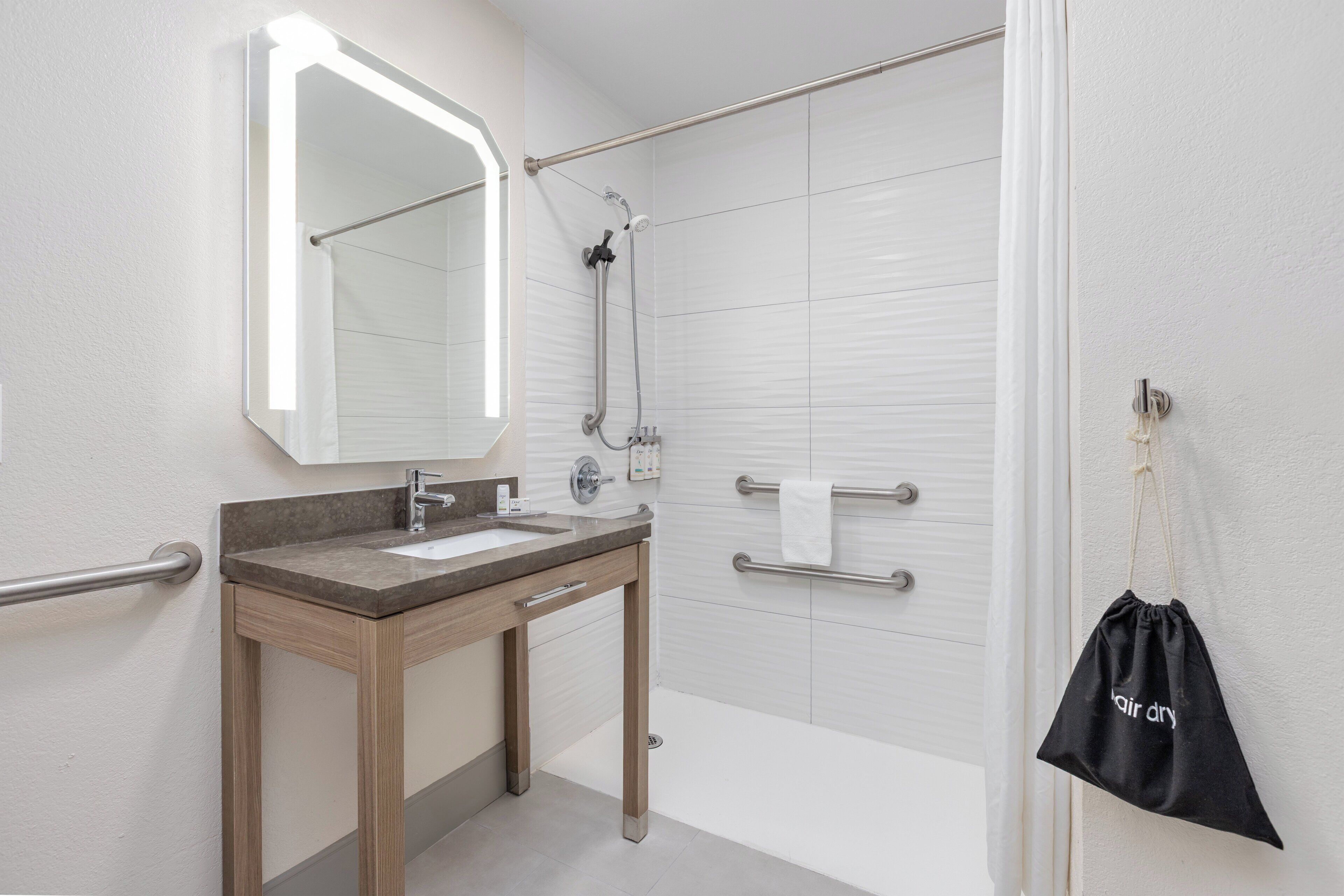 A modern bathroom with a vanity, mirror, shower, and towel rack.