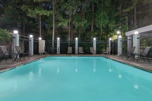 An outdoor swimming pool with a metal fence, lounge chairs, and a pergola with lights. - Candlewood Suites Houston (The Woodlands) by IHG (The Woodlands)