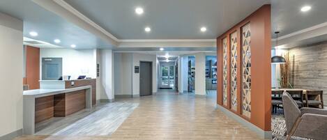 A spacious lobby with a reception desk, a dining area, and a hallway leading to other rooms.