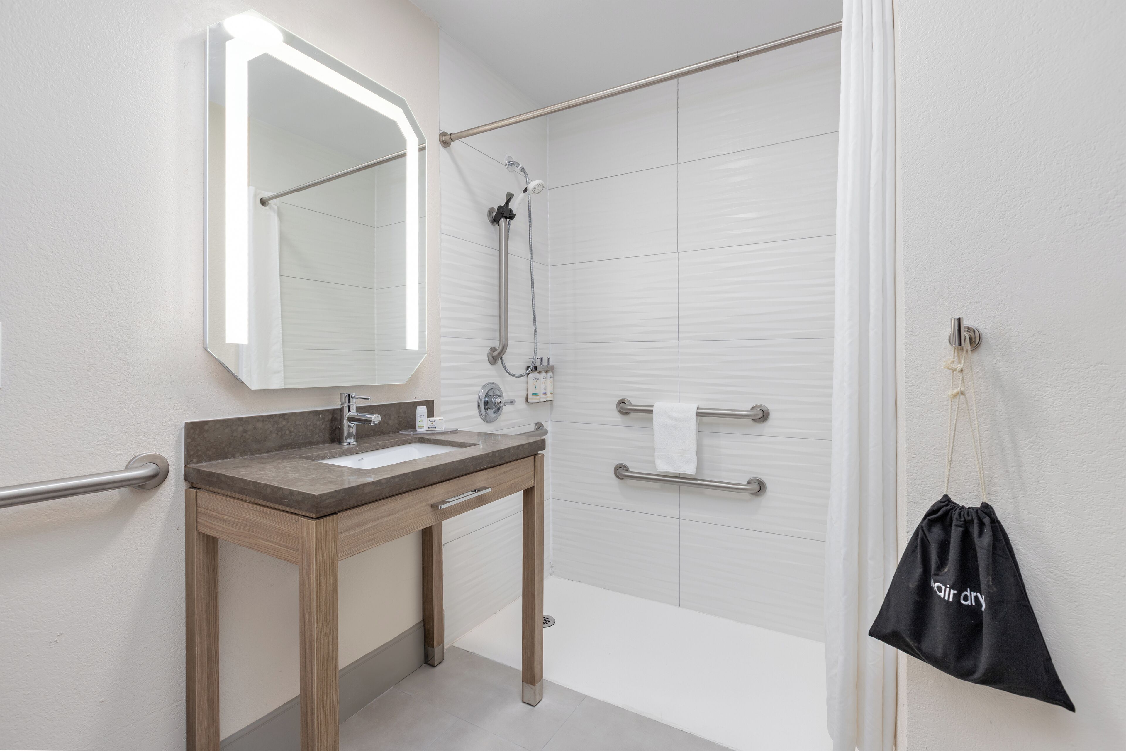Ein modernes Badezimmer mit Waschtisch, Spiegel, Dusche und Handtuchhalter.