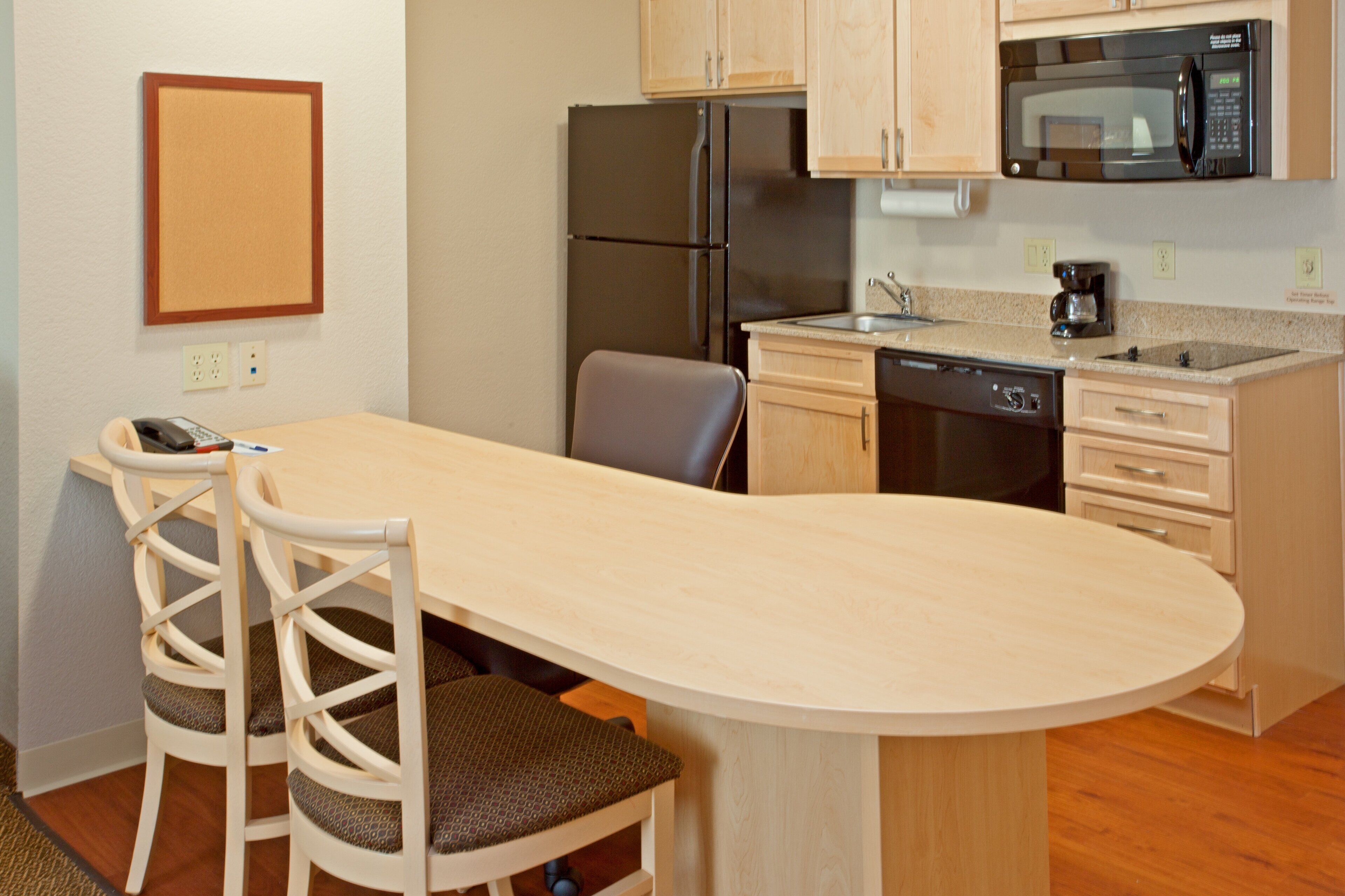 A compact kitchen with a refrigerator, microwave, and dishwasher. There is a small dining area with two chairs and a table.