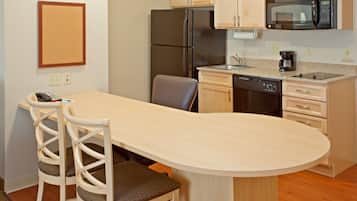 A compact kitchen with a refrigerator, microwave, and dishwasher. There is a small dining area with two chairs and a table.