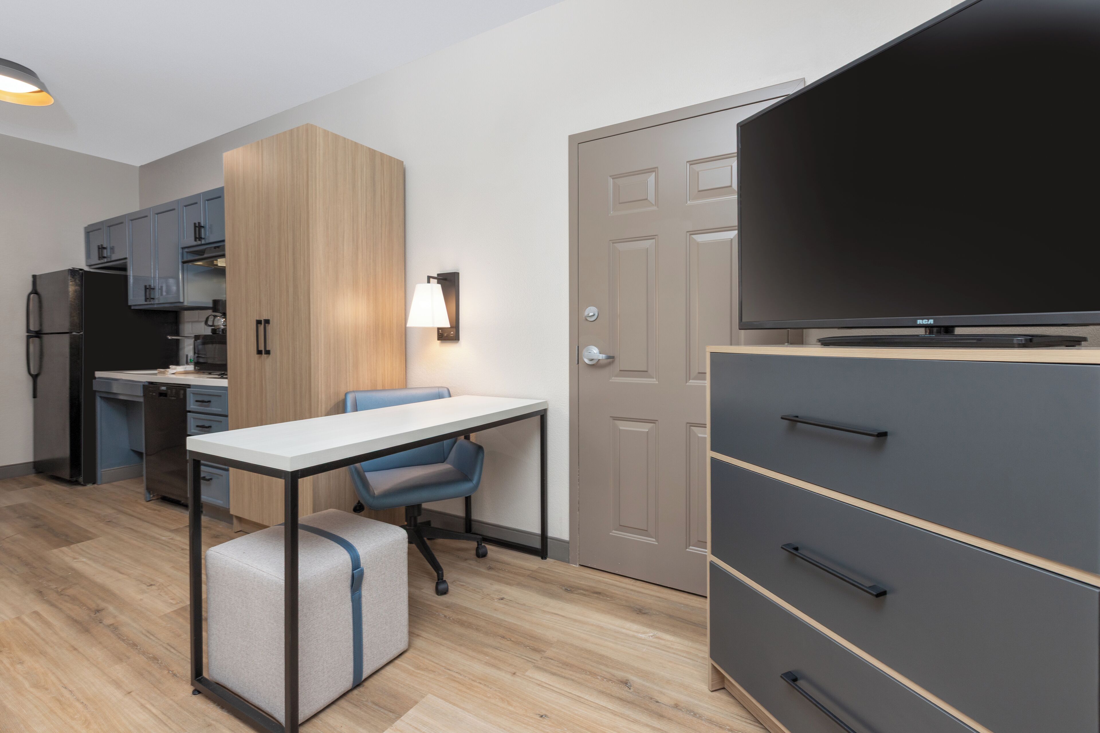 A compact kitchen with a dining area, a TV, and a wardrobe.
