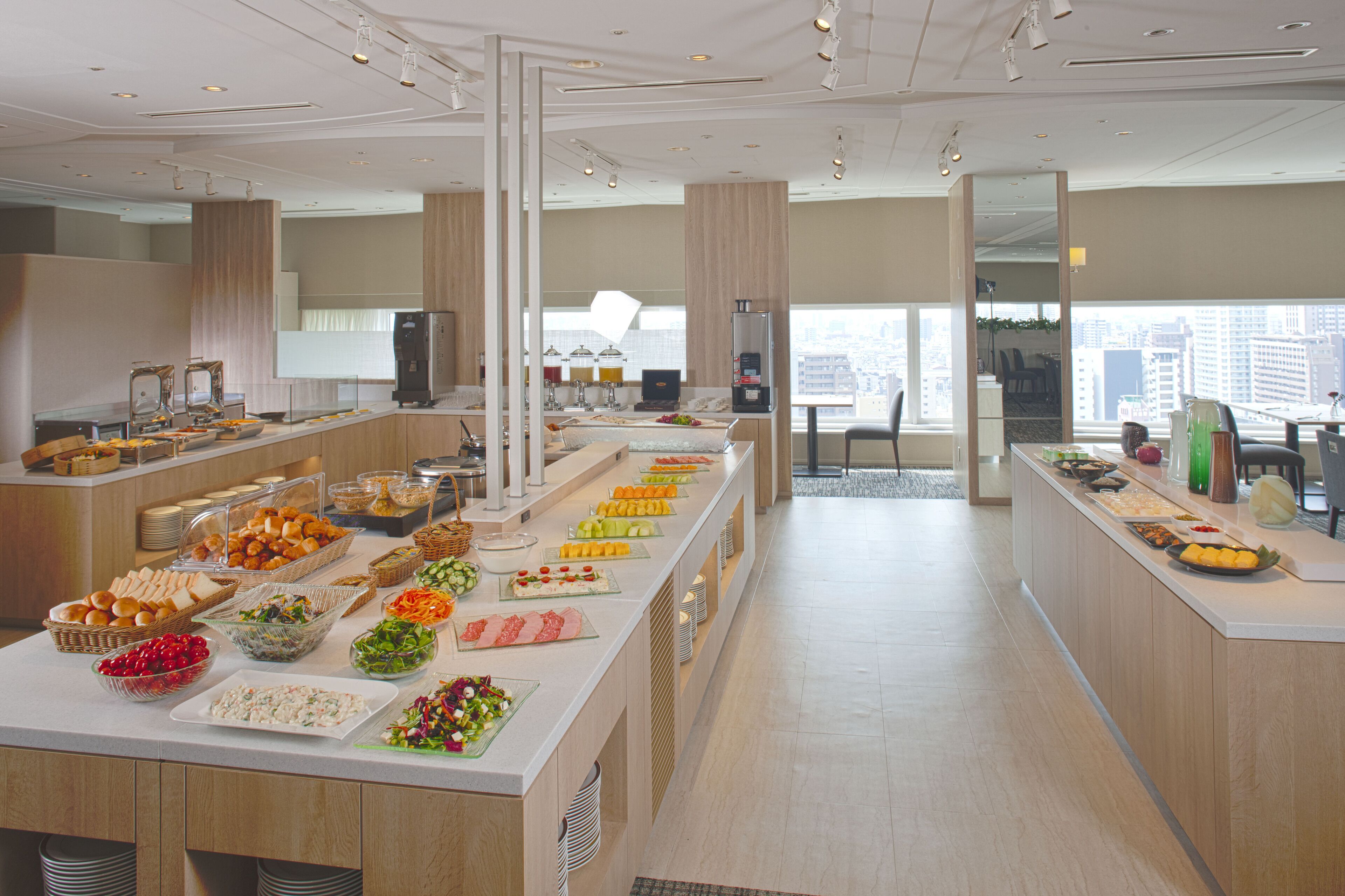 Un buffet proposant une variété de plats et offrant une vue sur la ville grâce à de grandes fenêtres.