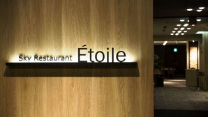A sign for Sky Restaurant Étoile with a wooden background.