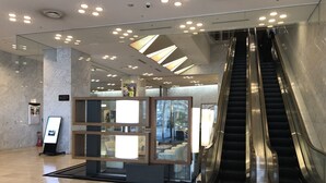 A modern interior with an escalator, a glass display case, and a sign indicating a location.