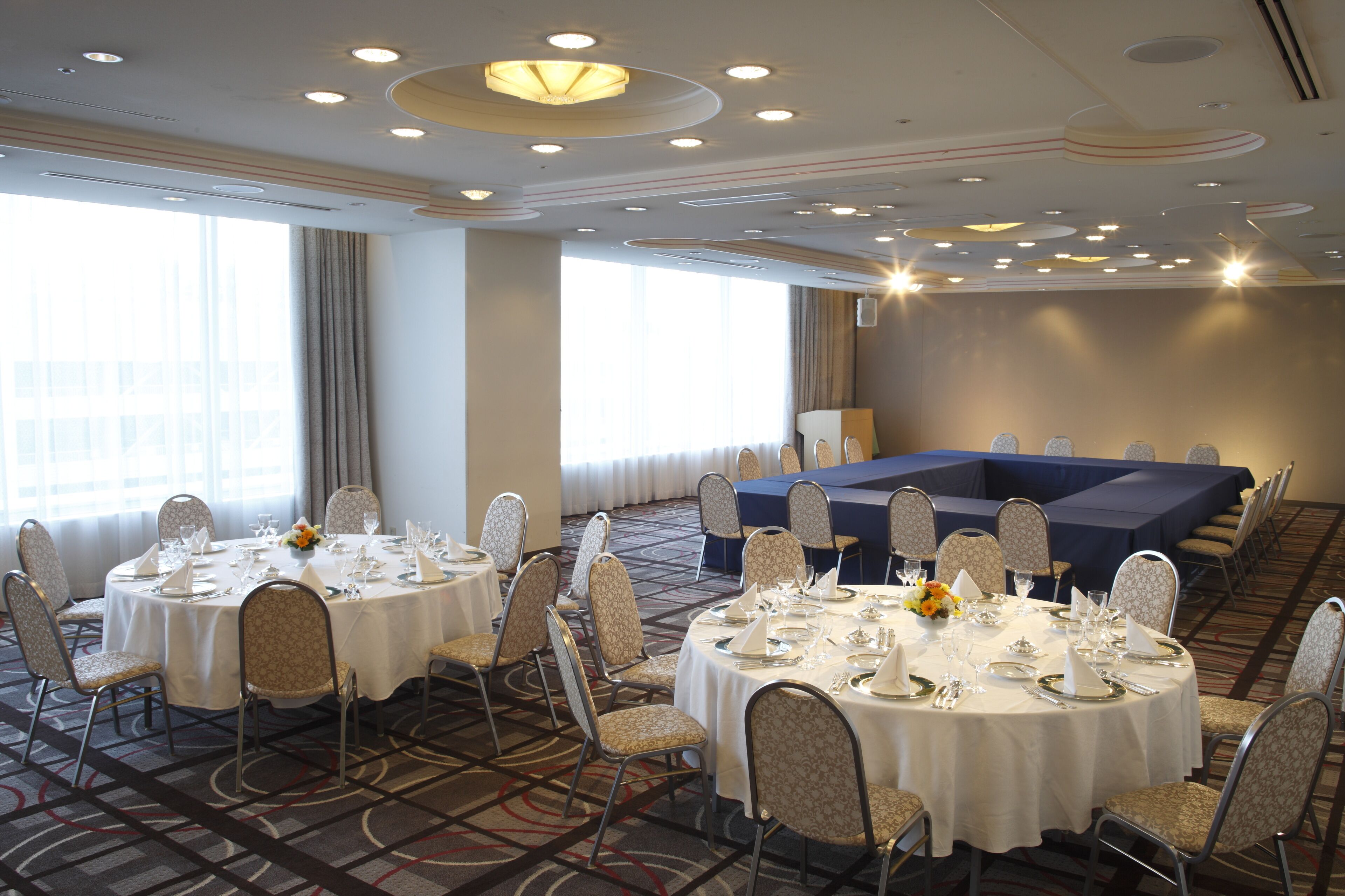 A conference room with round tables, chairs, and a stage area.