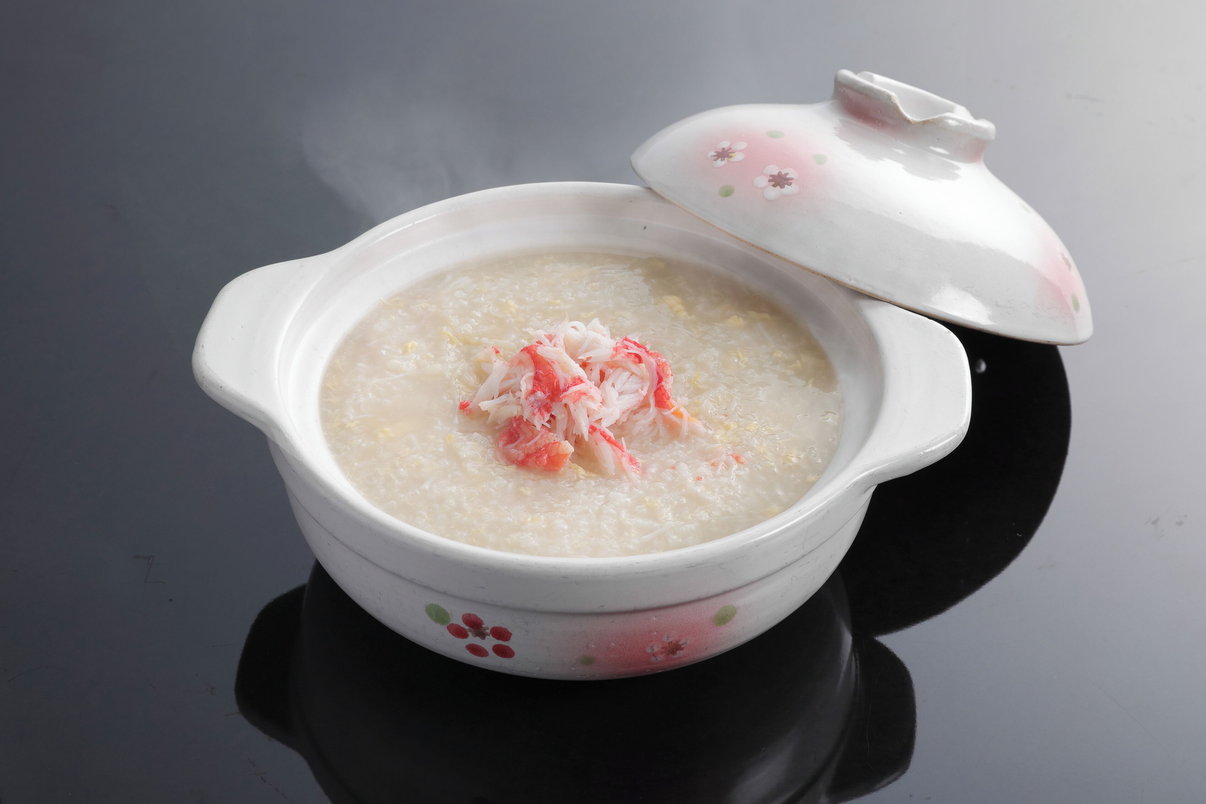 A bowl of porridge with a lid on a reflective surface.