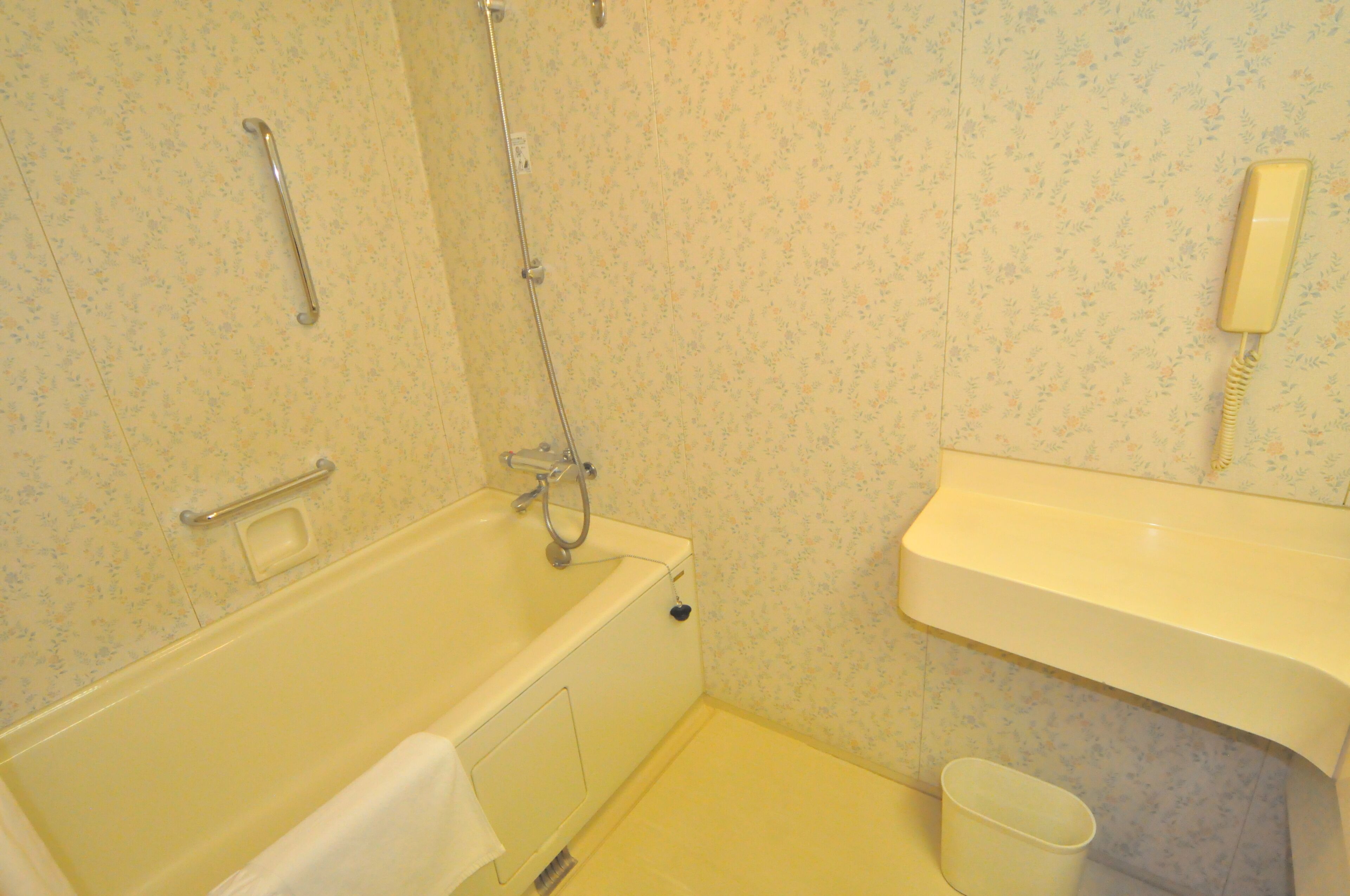 Un baño con bañera, inodoro, lavamanos, ducha de mano y teléfono.