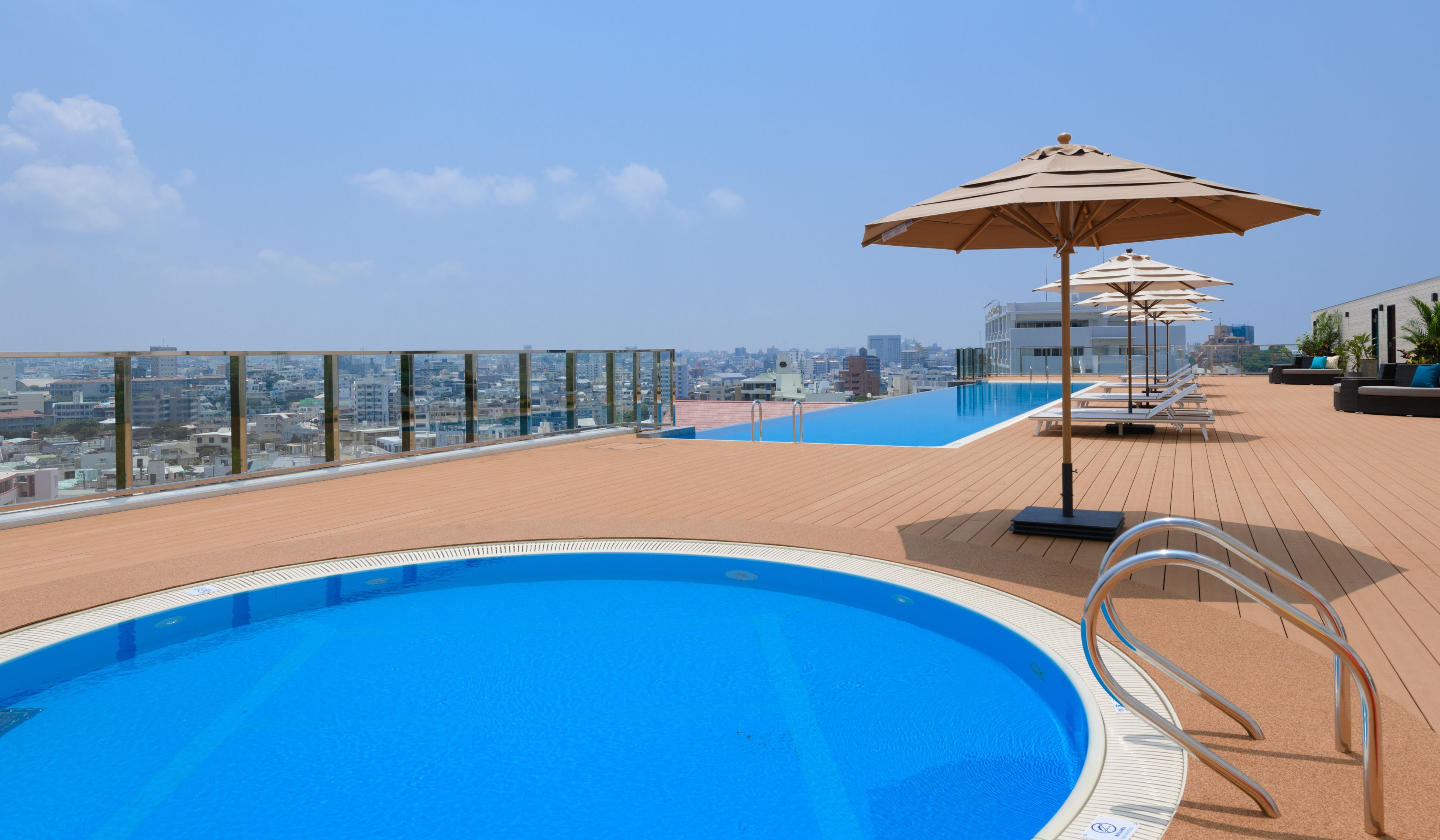 A rooftop pool with clear blue water, surrounded by wooden decking and lounge chairs.