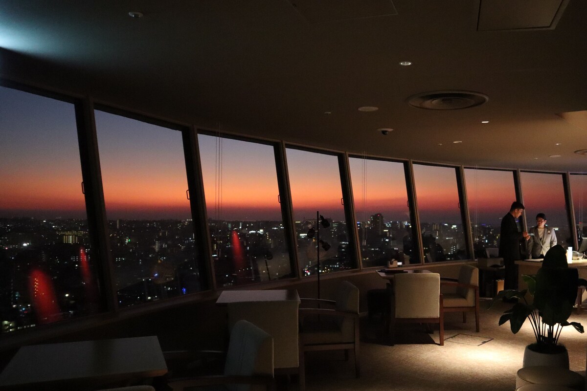 A modern office space with large windows offering a city view at dusk.
