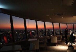 Un espacio de oficina moderno con amplios ventanales que ofrecen vista a la ciudad al atardecer.