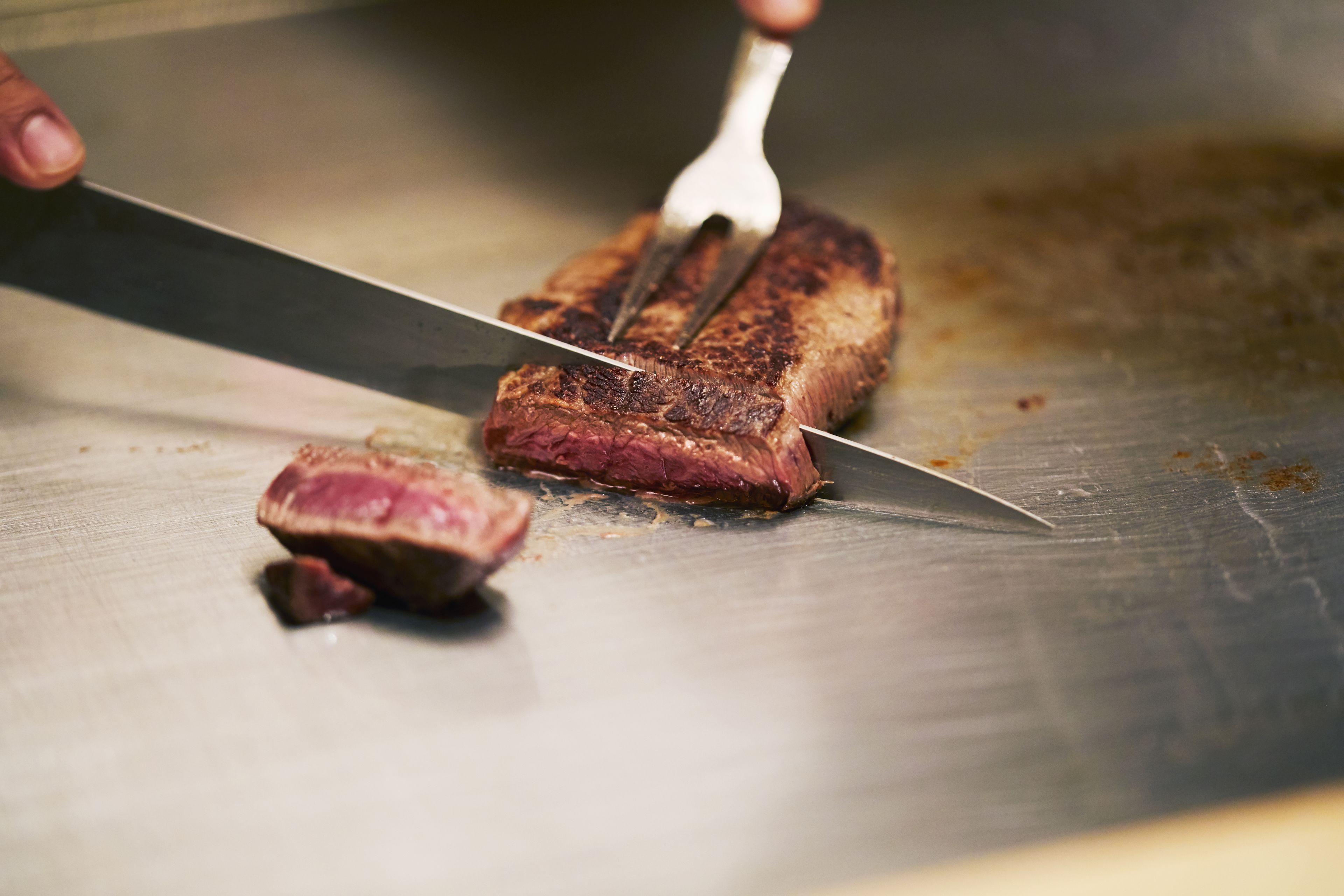 A steak being sliced on a cutting board.