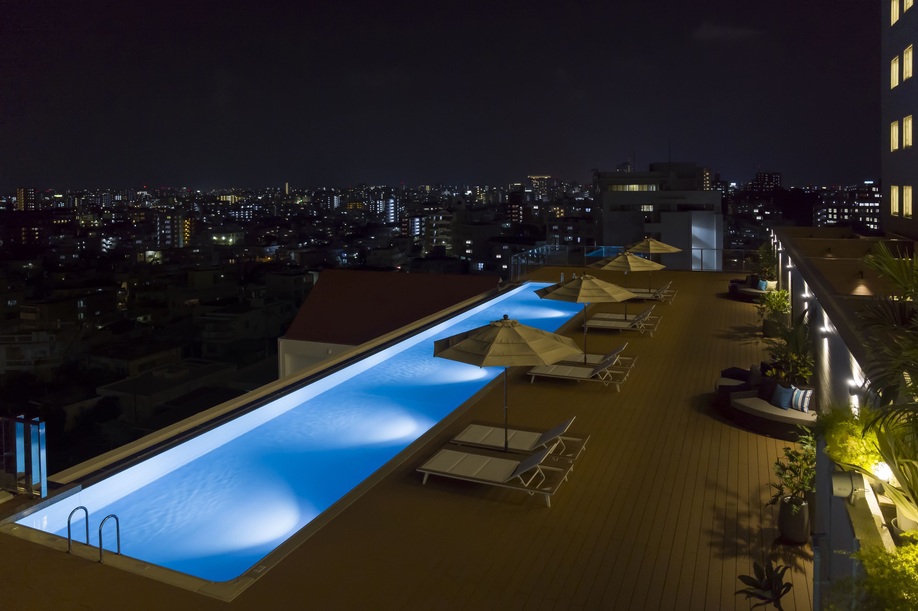 A rooftop pool with a view of the city at night.