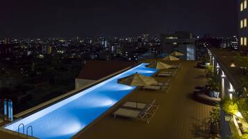 A rooftop pool with a view of the city at night.
