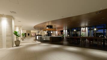 A spacious lobby with a central reception desk, seating areas, and large windows.