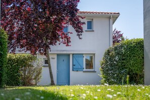 A two-story building with a blue door and windows, surrounded by greenery and a clear sky. - Résidence Odalys Le Domaine de l'Ocean (Saint-Brevin-les-Pins)