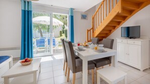 Eine moderne Küche mit weißen Schränken, einer Holztreppe und einem Essbereich mit gedecktem Tisch für das Frühstück.