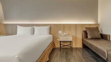 A hotel room with a bed, bedside table, and a sofa.