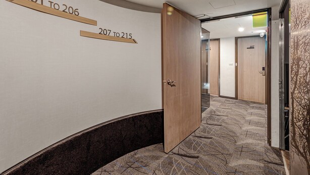 A hotel corridor with numbered doors, a wooden door, and a patterned carpet. - Guide Hotel Taipei Fuxing N (Taipei)