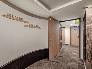 A hotel corridor with numbered doors, a wooden door, and a patterned carpet. - Guide Hotel Taipei Fuxing N (Taipei)