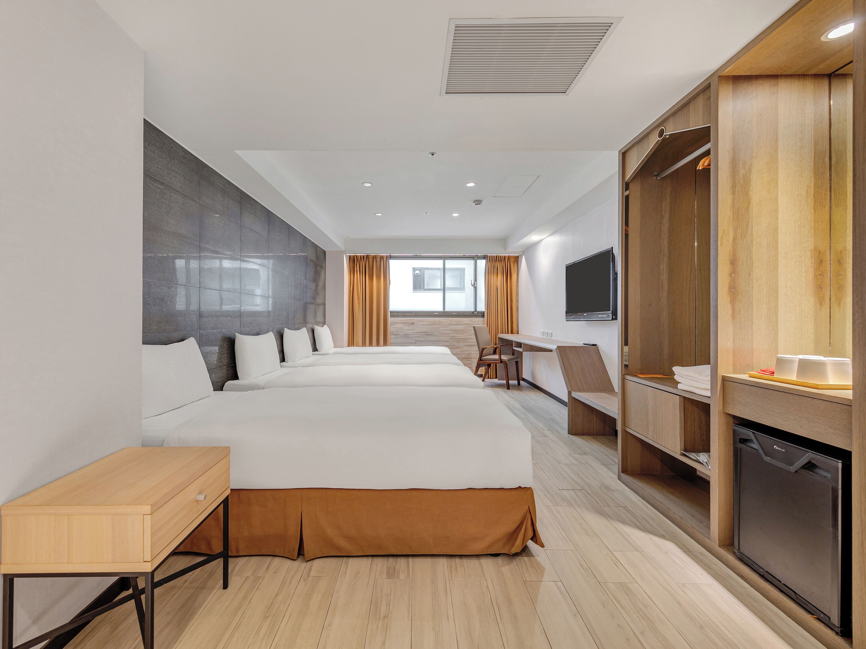 A hotel room with a large bed, a desk, a television, and a minibar.