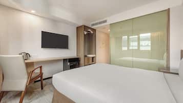 Een hotelkamer met een bed, een bureau, een televisie en een glazen schuifdeur.