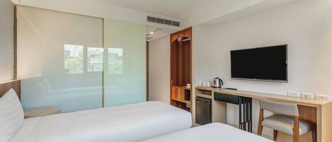 Habitación de hotel moderna con dos camas, un escritorio, televisión y vistas a la ciudad.
