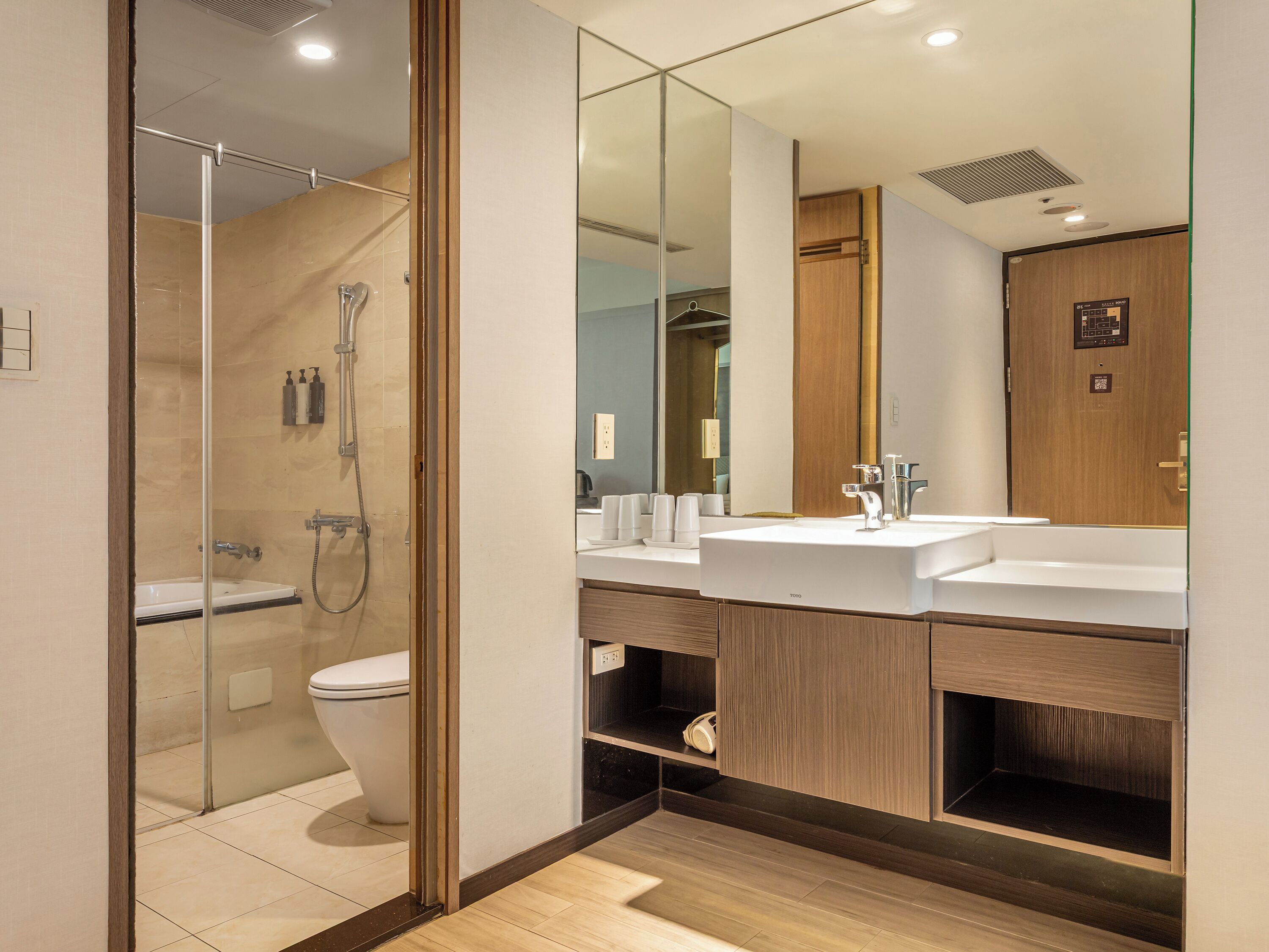 A modern bathroom with a glass-enclosed shower, a white sink, and a large mirror.